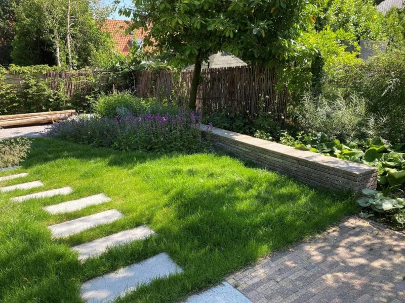 Haselnuss Zaun Somme 180 mit den Maßen 180 cm breit und 180 cm hoch als Zaun in einem grünen Garten.