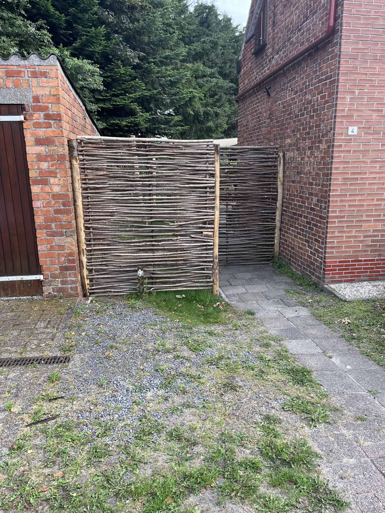 Haselnuss Zaun Somme 1 in der Größe 150 cm breit und 180 cm hoch als kreativer Zaun zwischen Haus und Scheune.