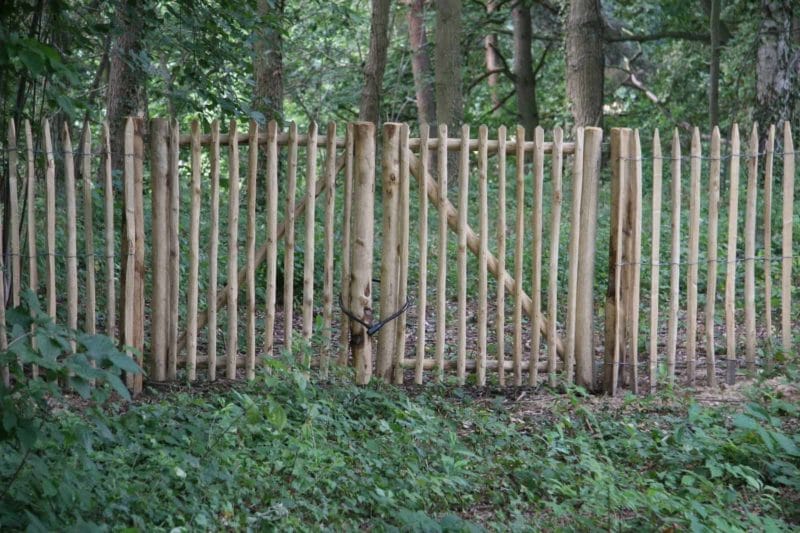 Dubbele Franse rondhoutpoort van 100 cm breed en 120 cm hoog per poortdeel tussen een schapenhek afrastering van 120 cm hoog in een bos.