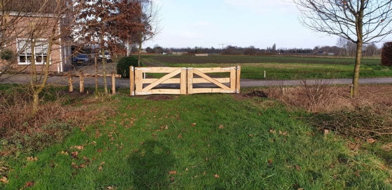 Dubbele kastenje boerenlandhek van 205 cm breed en 110 cm hoog met kastanje schaaldelen. Deze poort staat aan het begin van de wei als toegangspoort.