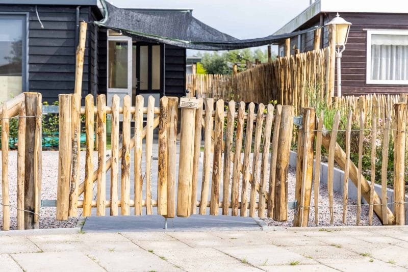 Dubbele Franse rondhoutpoort van 80 cm breed bij 80 cm hoog per poortdeel gebruikt als toegang naar de tuin bij een woning.