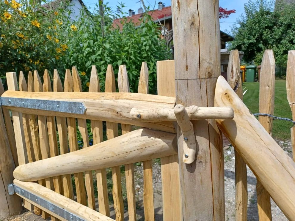 Franse rondhoutpoort in tuin met rustieke sluiting van hout