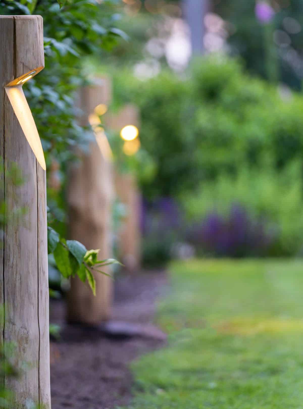 Rond houten tuinverlichting Billy in tuin met veel bloemen