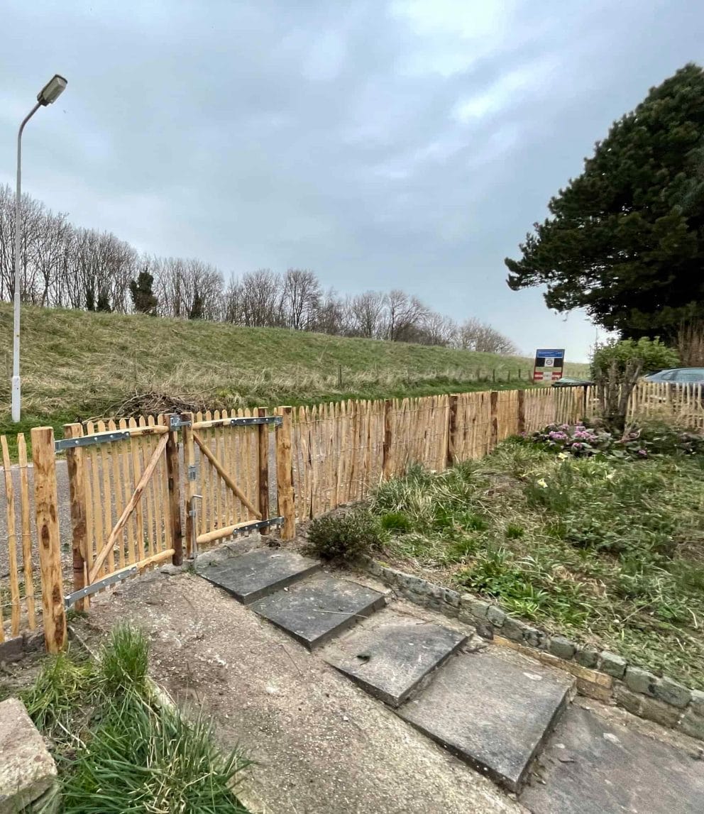 Dubbele Franse rondhoutpoort van 100 cm hoog en 80 cm breed per poortdeel als toegangspoort van de weg naar de tuin toe.