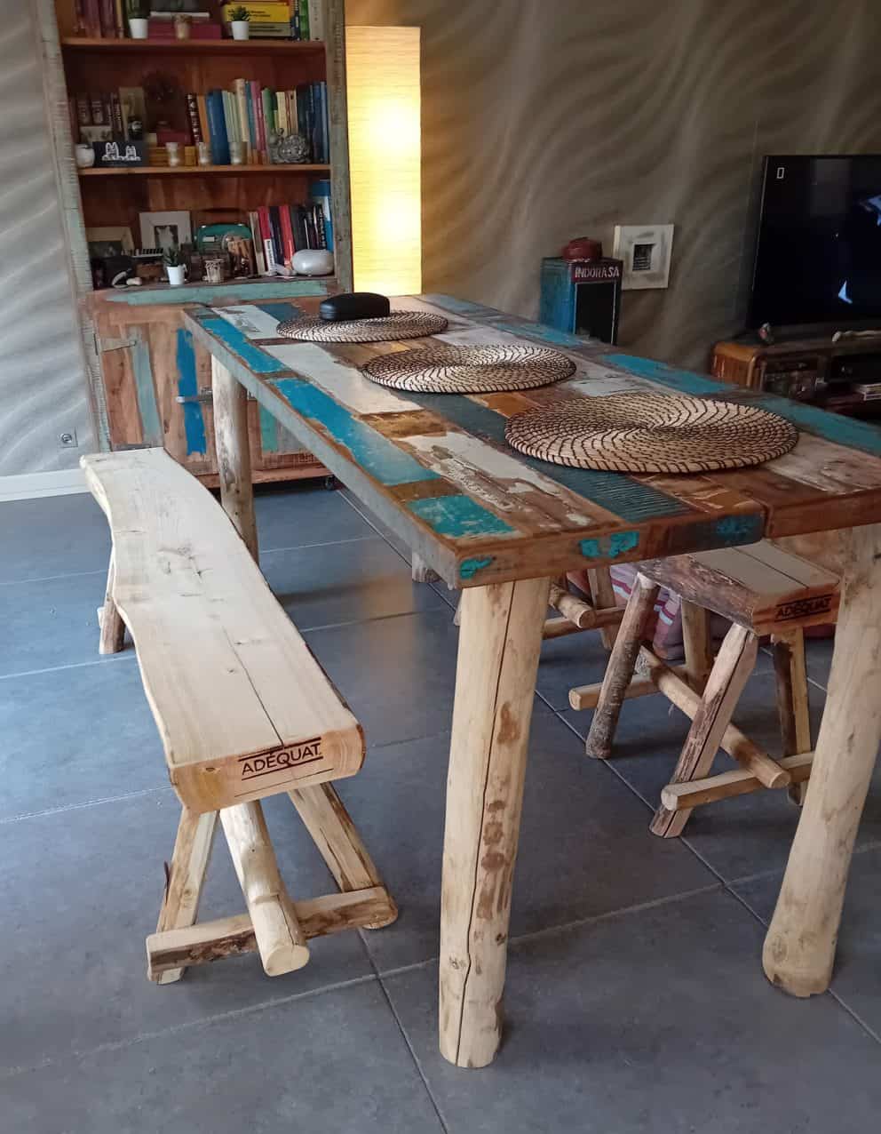 Boomstambankje van kastanjehout van 150 cm breed en twee kastanjehouten krukjes. Deze staan bij een tafel binnen in de woning. De bankjes en de tafel stralen een Ibiza look uit.