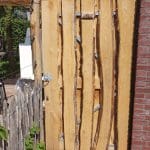 Poort gemaakt van kastanjehouten schaaldelen in de maat 2x15 - 22x250 cm De poort is bevestigd aan de zijkant van het huis en wordt gebruikt als toegangspoort naar de tuin.