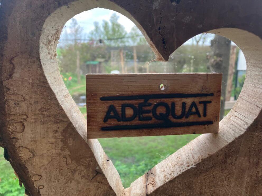Close up Adéquat logo plankje in uitgesneden houten hart
